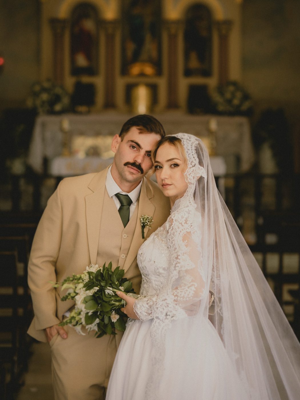 Noivos na igreja com buquê de flores brancas