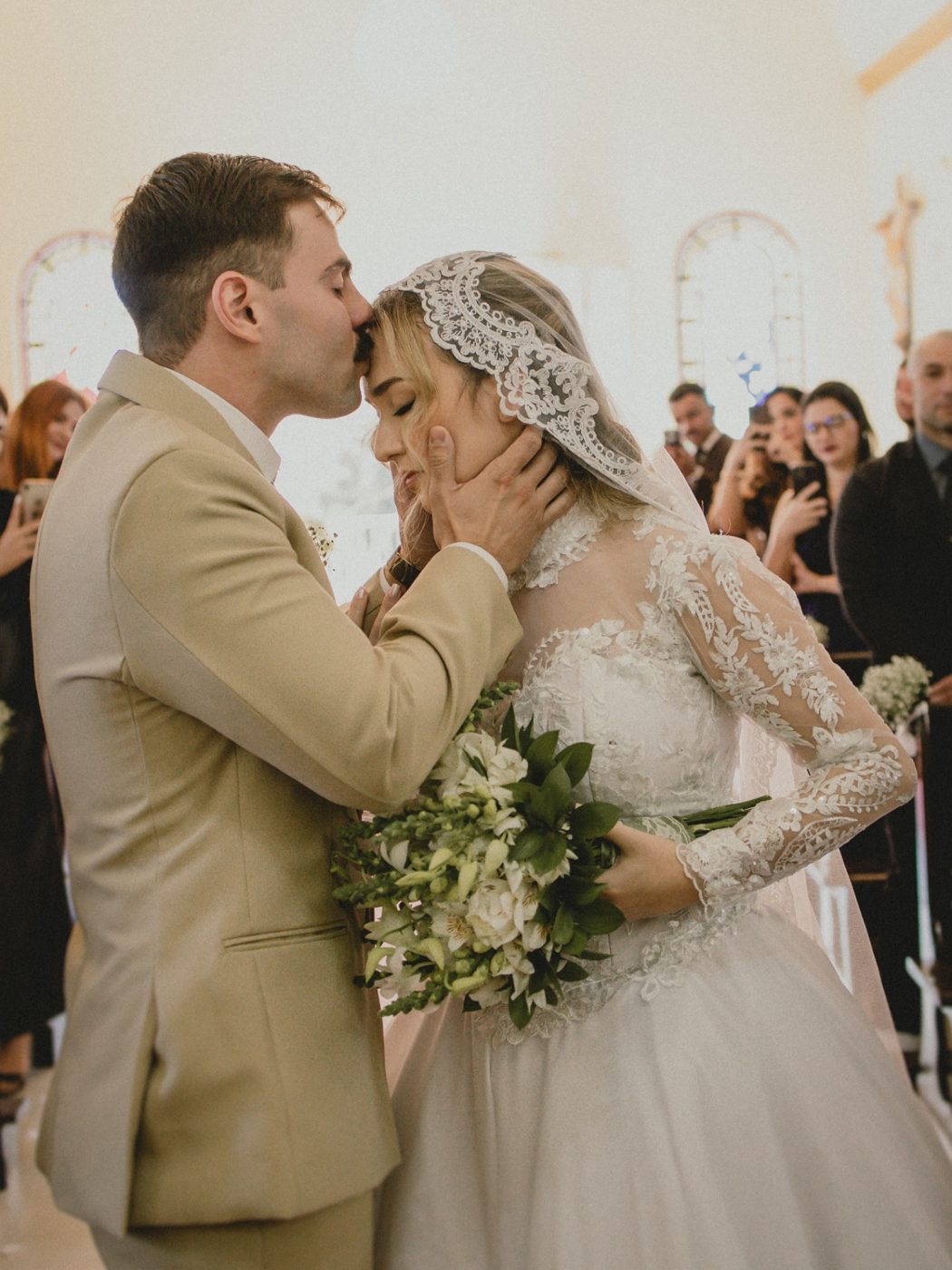 Noivo beijando a testa da noiva na cerimônia
