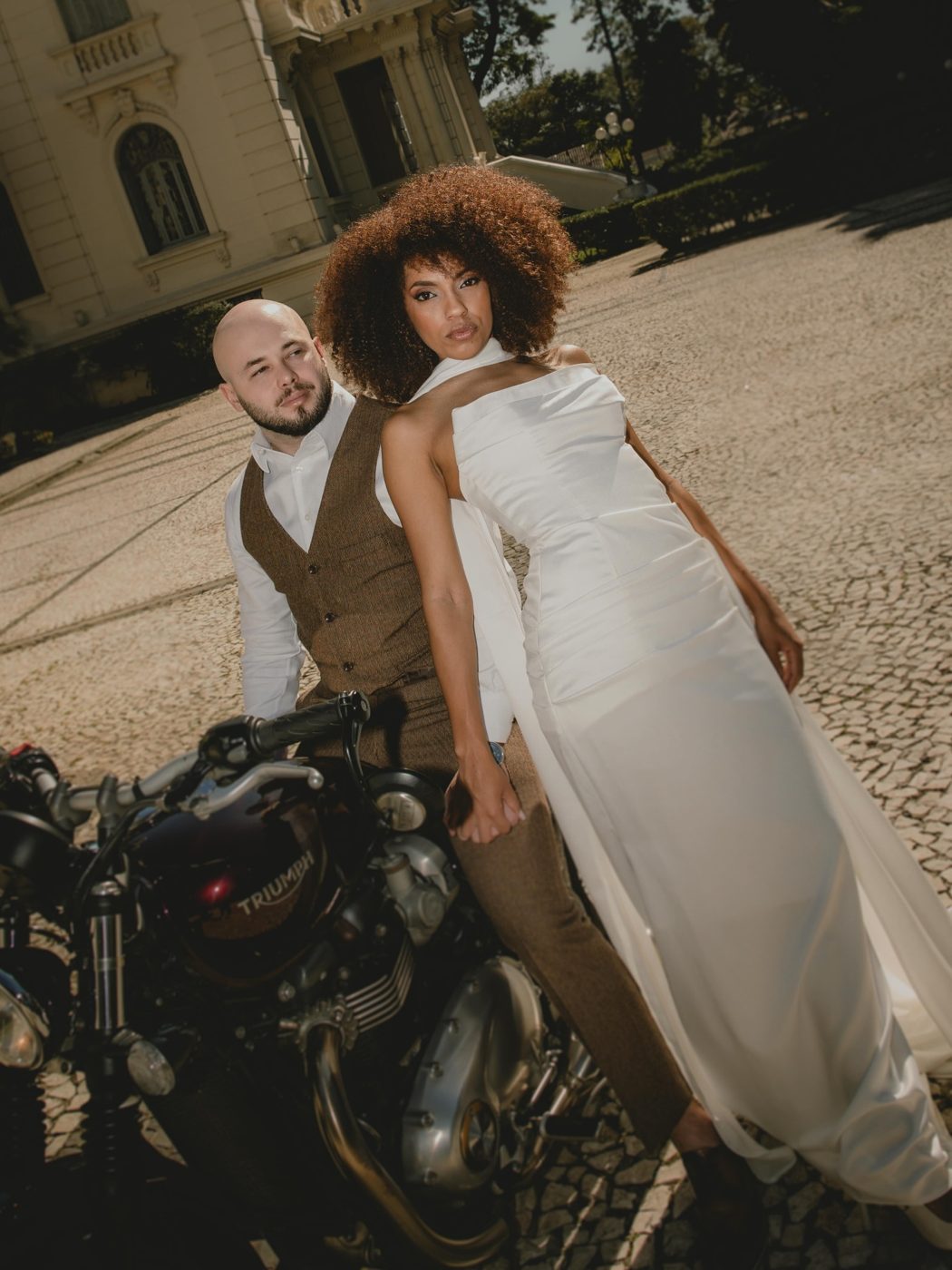 Casal ao lado de moto clássica em ensaio urbano